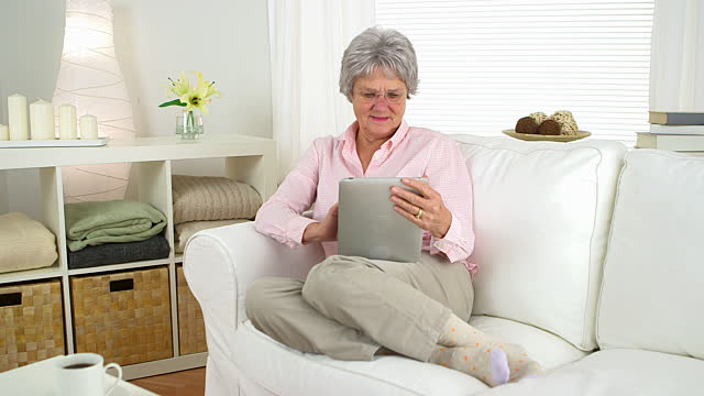 elderly lady sitting on couch with iPad 